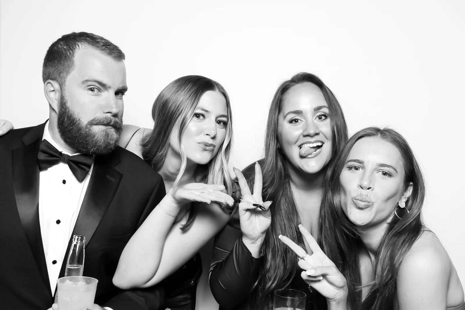Four formal-event guests posing in a black and white photo booth portrait