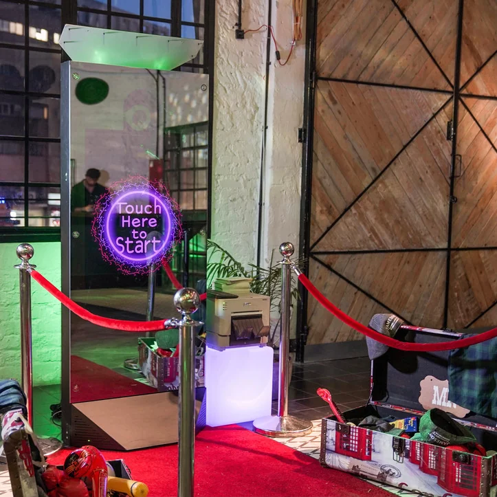 Magic Mirror touchscreen booth lit in green with a red carpet at an event