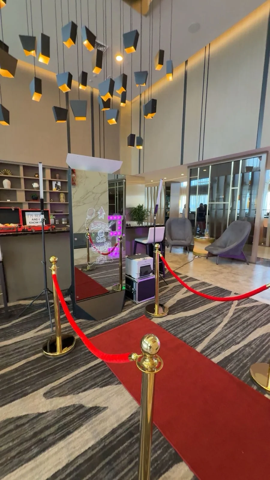 A mirror photo booth with red velvet ropes in a modern celebration venue
