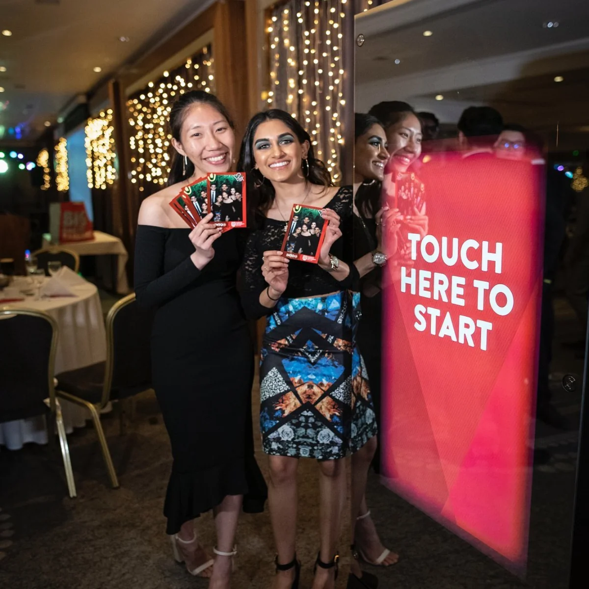 Wedding celebration guests holding their photo prints beside the interactive booth